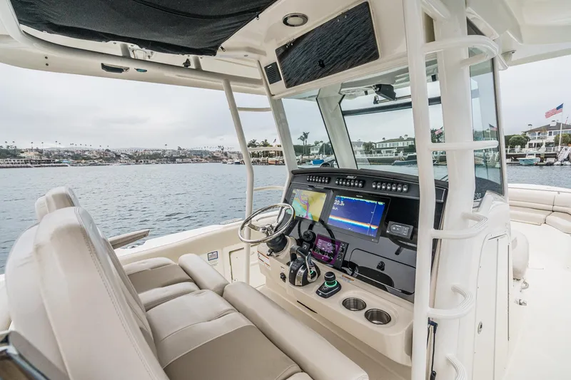 Slide: The Image of 2019 Boston Whaler 330 Outrage helm with advanced navigation system, docked in a scenic marina. - 45