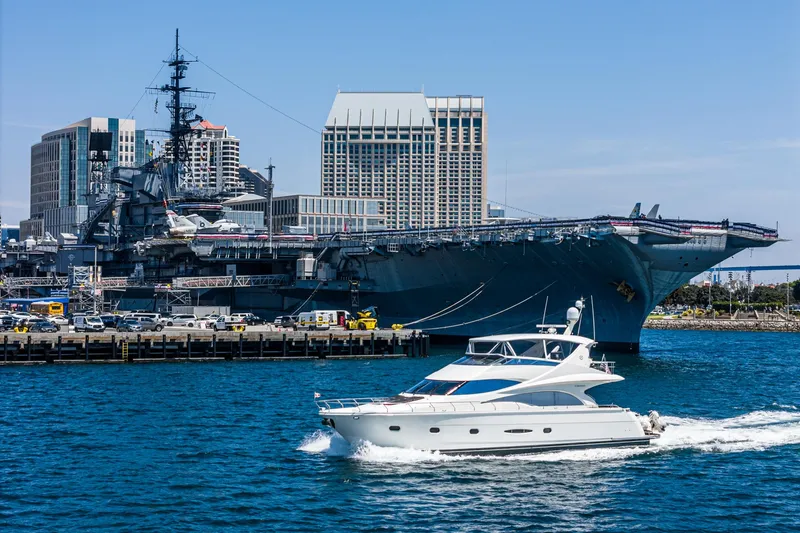 Slide: The Image of Luxury 2004 Marquis yacht cruising near a large battleship in a city harbor. - 44