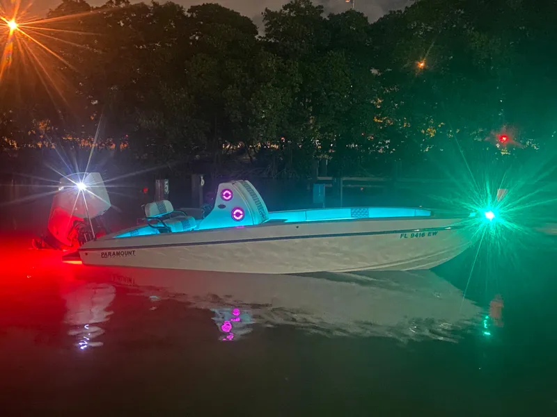 Slide: The Image of 1987 Paramount 21 boat illuminated with colorful lights on water at night. - 16