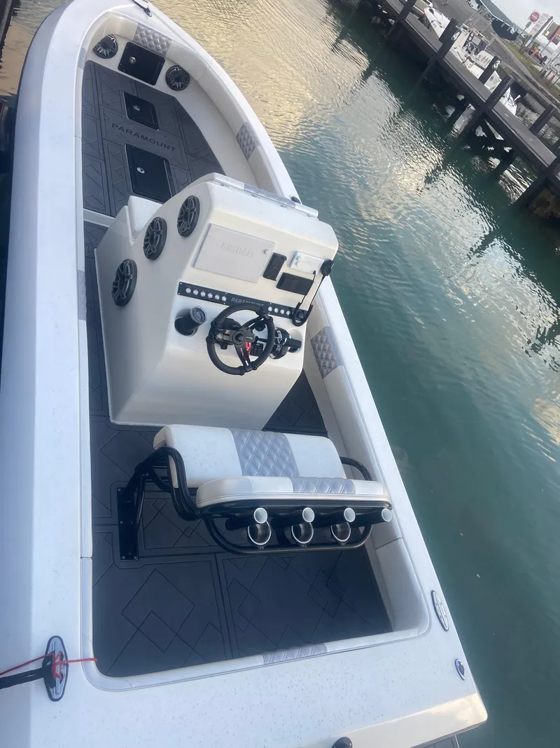 Slide: The Image of 1987 Paramount 21 boat docked, featuring modern console and seating, on calm water. - 7