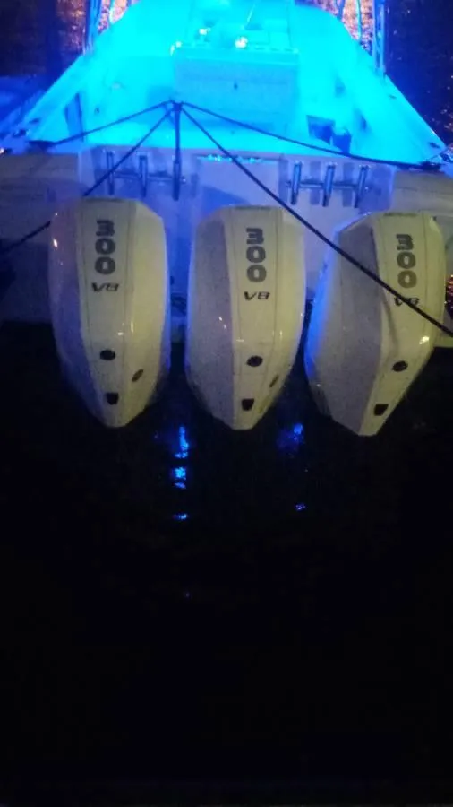 Slide: The Image of 2001 Intrepid 366 Cuddy with triple outboard motors, illuminated by blue lights at night. - 20