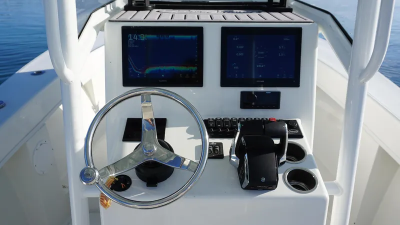 Slide: The Image of 2023 Pair Customs 25 Center Console boat dashboard with steering wheel and navigation screens. - 8