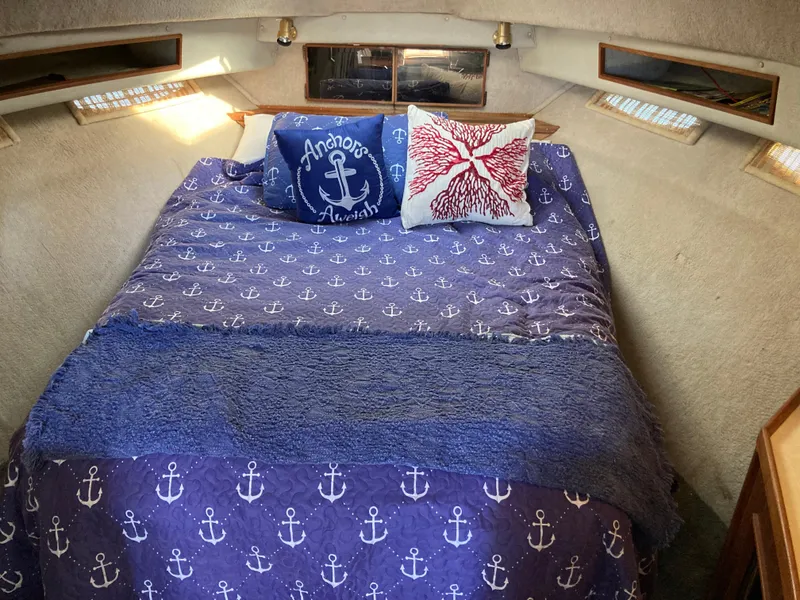 Slide: The Image of Cozy cabin interior of 1986 Sea Ray 340 Express Cruiser with nautical-themed bedding. - 18