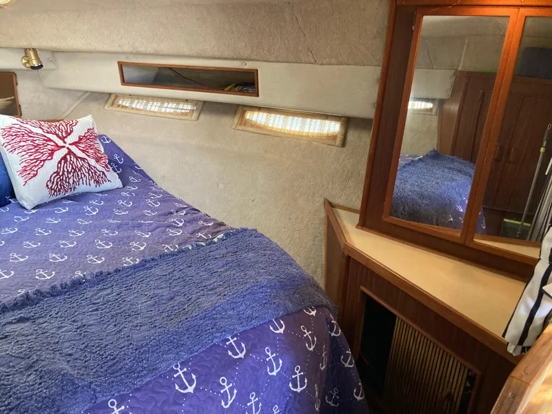 Slide: The Image of 1986 Sea Ray 340 Express Cruiser cabin with nautical bedding and wooden cabinetry. - 20