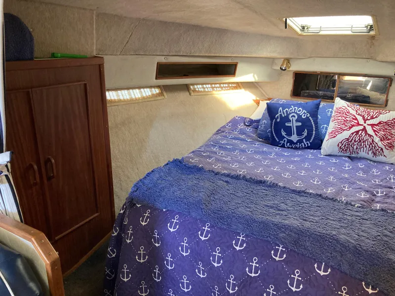Slide: The Image of Cozy cabin interior of 1986 Sea Ray 340 Express Cruiser with nautical-themed bedding. - 21