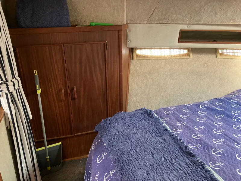 Slide: The Image of Interior of 1986 Sea Ray 340 Express Cruiser with nautical-themed bedding and wooden cabinet. - 22