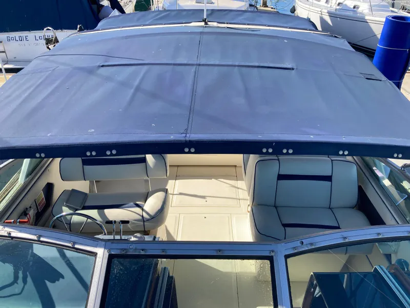 Slide: The Image of 1986 Sea Ray 340 Express Cruiser with blue canopy and white seating. - 26