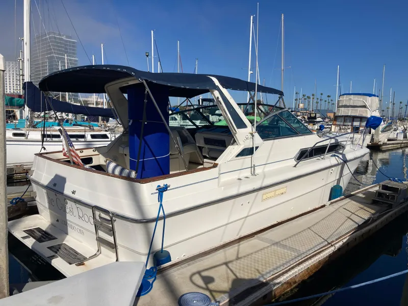 Slide: The Image of 1986 Sea Ray 340 Express Cruiser docked at marina, blue canopy, clear sky. - 28
