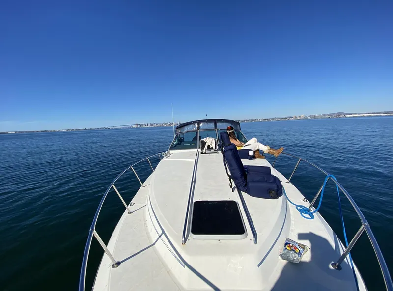 Slide: The Image of 1986 Sea Ray 340 Express Cruiser on calm water, person relaxing on deck. - 29
