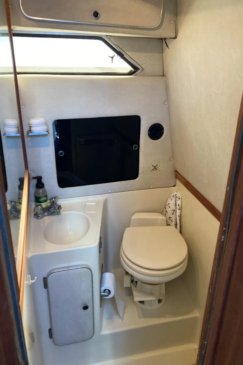 Slide: The Image of 1986 Sea Ray 340 Express Cruiser bathroom with sink, toilet, and storage. - 40