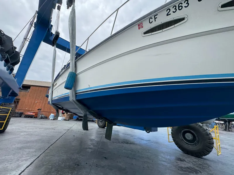 Slide: The Image of 1986 Sea Ray 340 Express Cruiser on lift, showcasing hull and boatyard setting. - 47