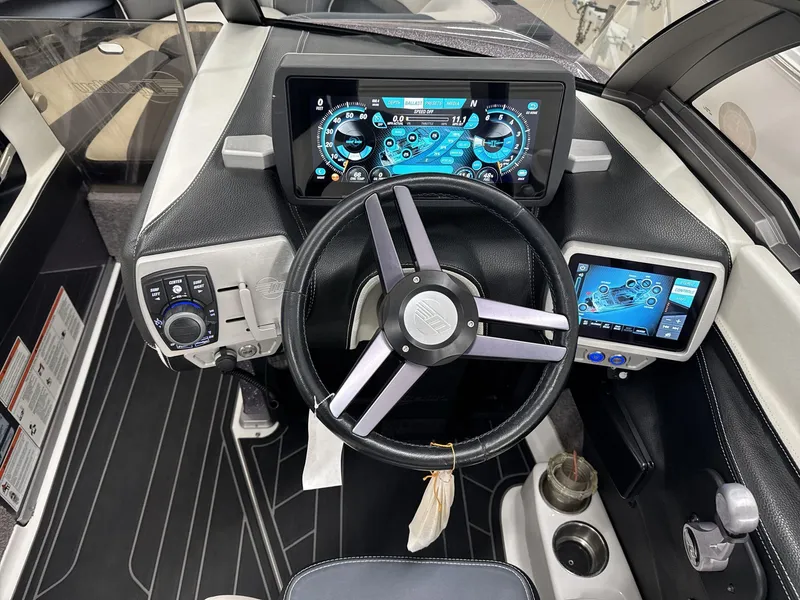 Slide: The Image of 2016 Malibu 25 LSV boat dashboard with digital displays and steering wheel. - 13