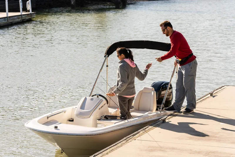 Slide: The Image of 2024 Boston Whaler 150 Montauk boat docked with two people on board. - 17