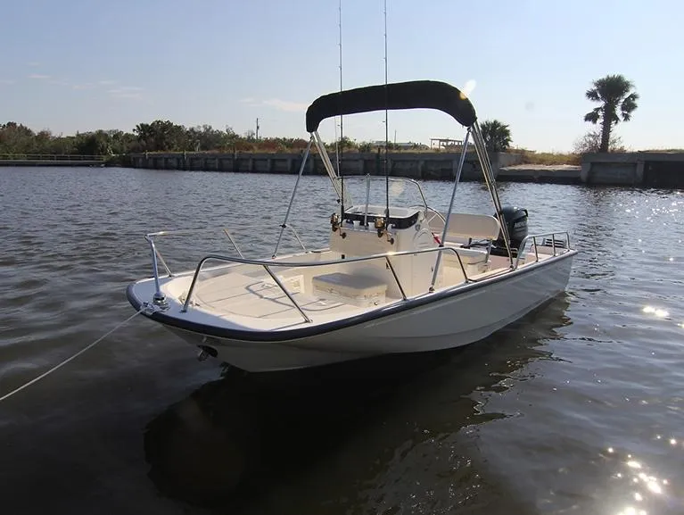 Slide: The Image of 2024 Boston Whaler 150 Montauk boat on calm water with bimini top. - 22