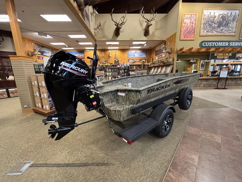 Slide: The Image of 2025 Tracker Grizzly 1650 T Prairie Wings Edition boat displayed indoors with Mercury outboard motor. - 4