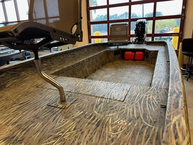 Slide: The Image of 2025 Tracker Grizzly 1650 T Prairie Wings Edition boat with camo interior in showroom. - 2