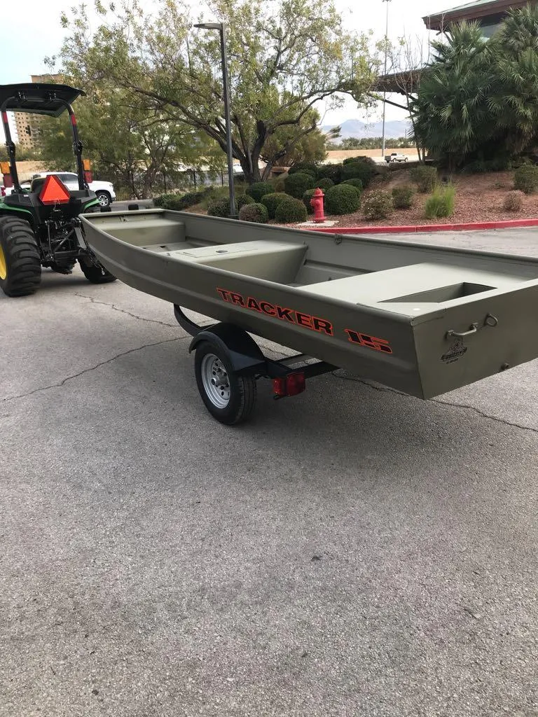 Slide: The Image of 2025 Tracker Grizzly 1542 Utility boat on trailer, parked outdoors. - 2