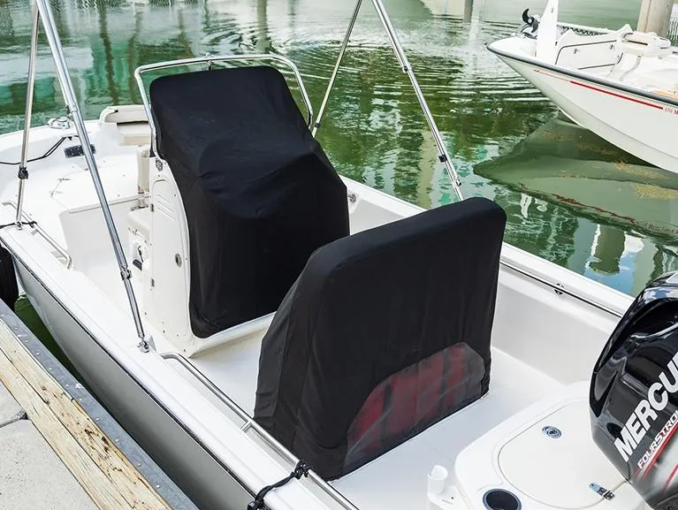 Slide: The Image of 2025 Boston Whaler 150 Montauk boat with covered seats, docked by the water. - 18