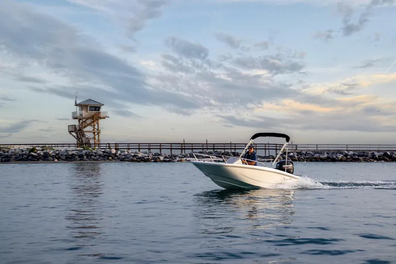 Slide: The Image of 2024 Boston Whaler 160 Super Sport cruising near a scenic pier at sunset. - 21