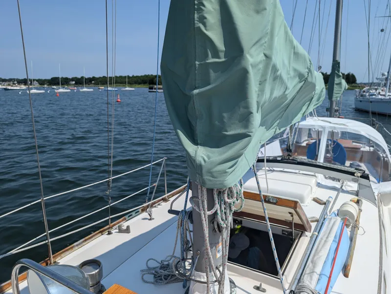 Slide: The Image of Hinckley Bermuda 40 Yawl, 1974, docked sailboat with covered mast and scenic harbor view. - 10