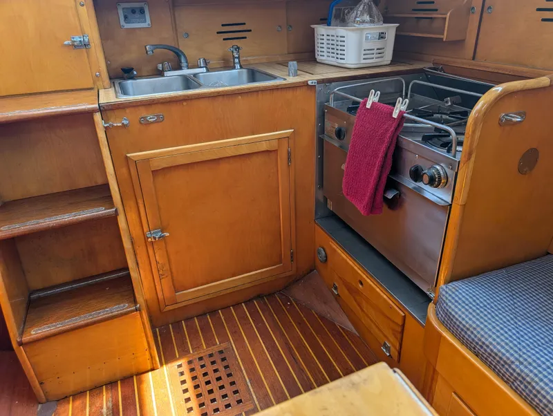 Slide: The Image of Interior of 1974 Hinckley Bermuda 40 Yawl, featuring a compact wooden kitchen area. - 40