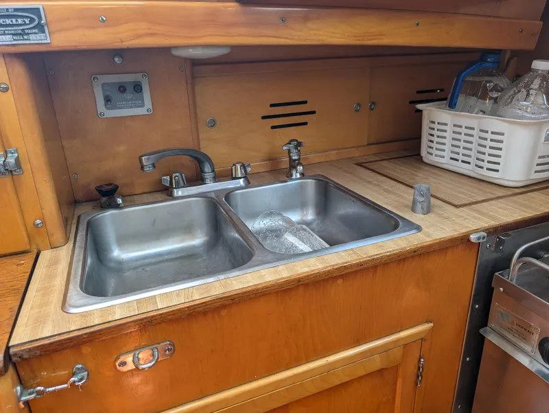 Slide: The Image of 1974 Hinckley Bermuda 40 Yawl kitchen sink area with dual basins and wooden cabinetry. - 41