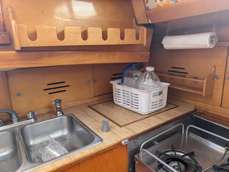 Slide: The Image of 1974 Hinckley Bermuda 40 Yawl kitchen with sink, stove, and wooden cabinetry. - 42