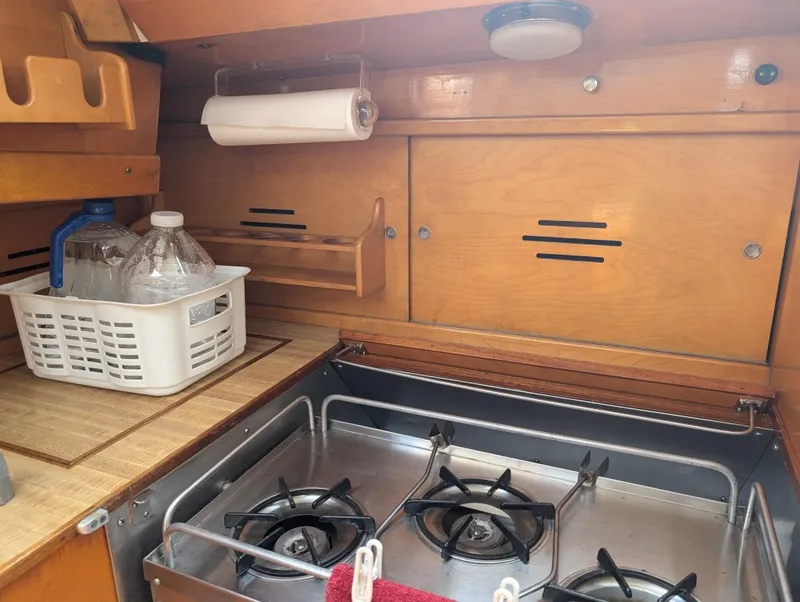 Slide: The Image of 1974 Hinckley Bermuda 40 Yawl galley with stove, wooden cabinets, and storage basket. - 43