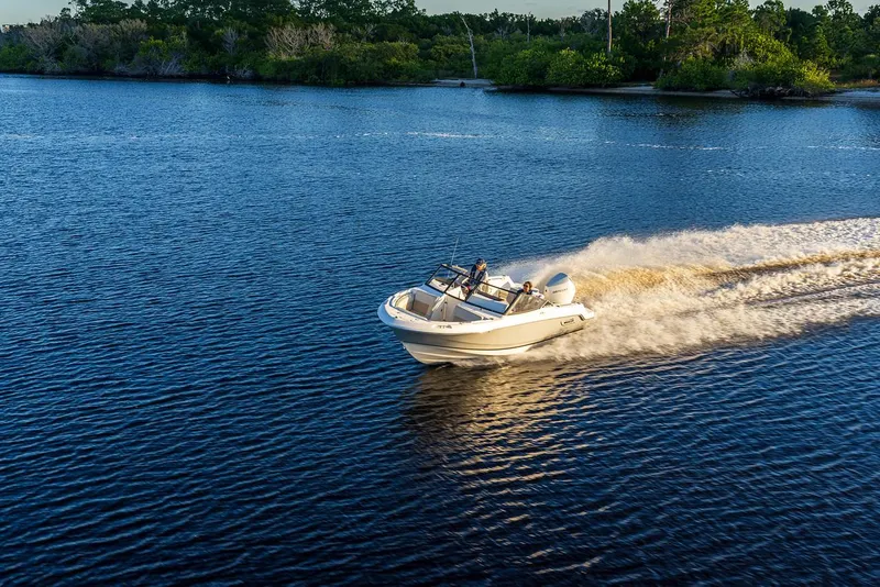 Slide: The Image of 2024 Boston Whaler 210 Vantage speeding on a serene lake. - 23
