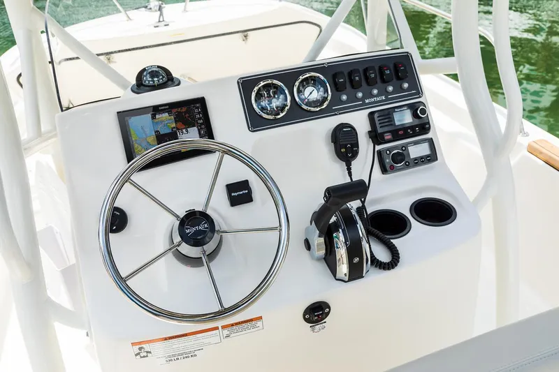Slide: The Image of 2025 Boston Whaler 190 Montauk boat dashboard with steering wheel and navigation controls. - 11
