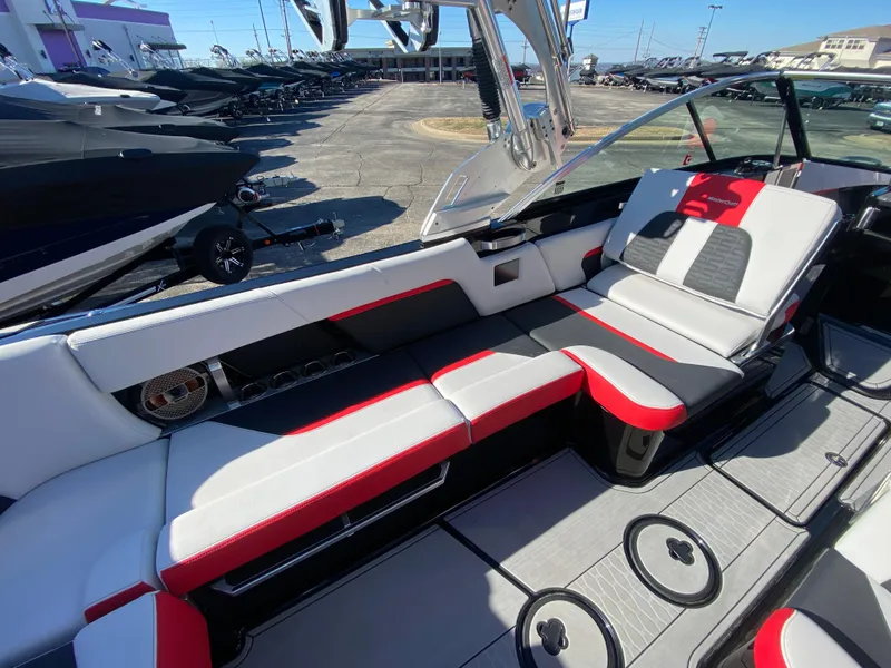 Slide: The Image of 2021 MasterCraft X26 boat interior with red and gray seating, docked outdoors. - 16