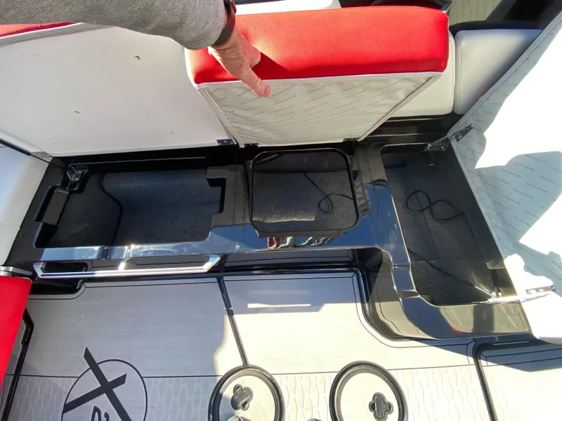 Slide: The Image of 2021 MasterCraft X26 boat interior storage compartments with red and white seating. - 17