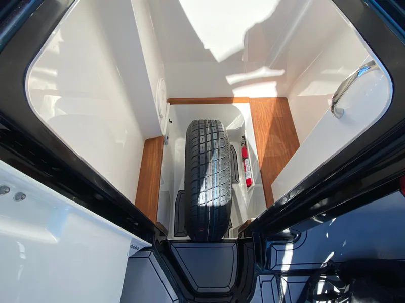 Slide: The Image of 2021 MasterCraft X26 storage compartment with spare tire and wooden flooring. - 28