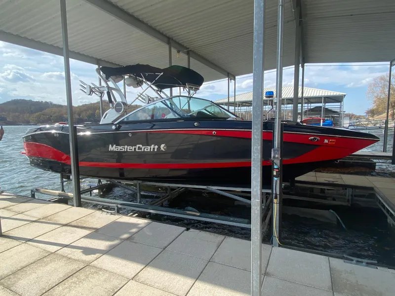 Slide: The Image of 2021 MasterCraft X26 boat docked, featuring sleek black and red design. - 43