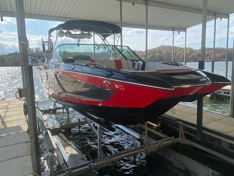 Slide: The Image of 2021 MasterCraft X26 boat in dock, featuring sleek black and red design. - 44