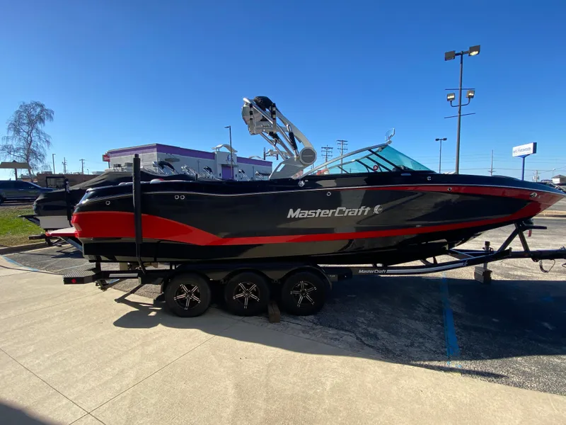 Slide: The Image of 2021 MasterCraft X26 boat on trailer, black and red design, parked outdoors. - 6