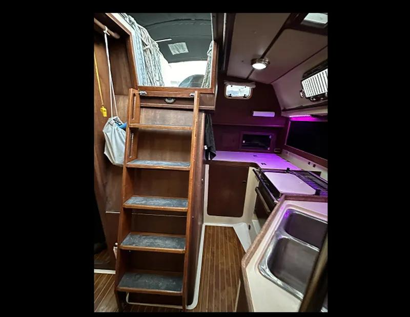 Slide: The Image of Interior of 1989 Canadian Sailcraft CS40 sailboat, featuring wooden stairs and compact kitchen area. - 28