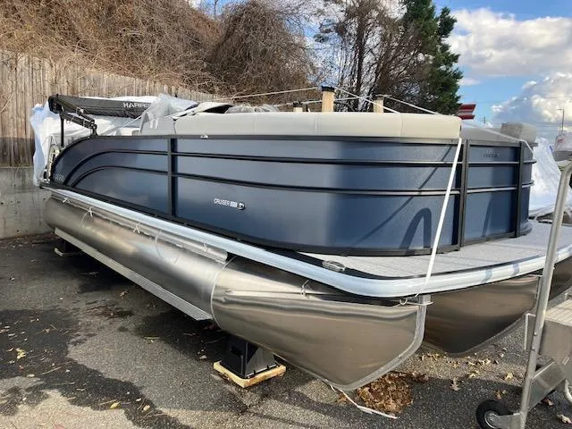 Slide: The Image of 2025 Harris Cruiser 210 pontoon boat parked outdoors on a trailer. - 1