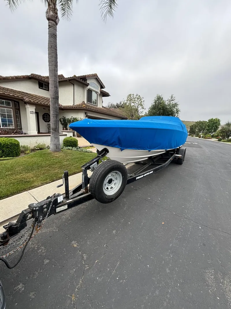 Slide: The Image of 1998 Wellcraft Scarab 30 boat on trailer with blue cover, parked on residential street. - 10