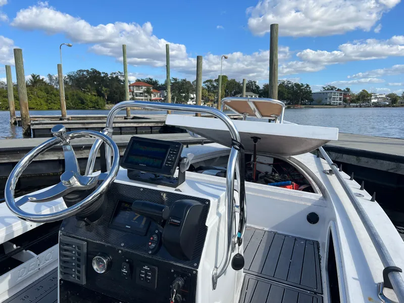 Slide: The Image of 2024 Deno 17 Flats boat at dock, featuring steering wheel and navigation system. - 5