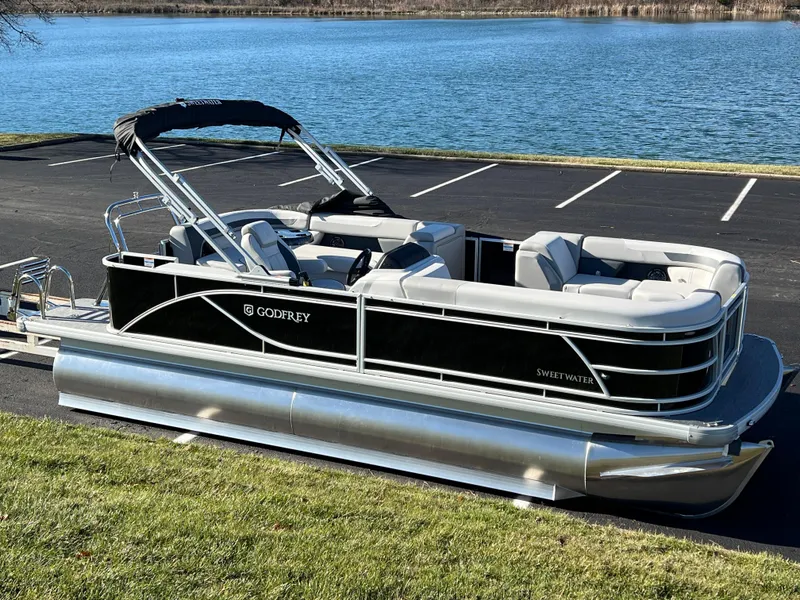 Slide: The Image of 2025 Godfrey Sweetwater 2286 C Special Edition pontoon boat by a lake. - 1
