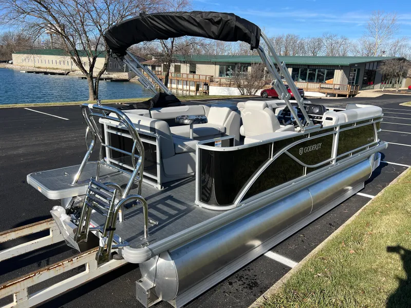 Slide: The Image of 2025 Godfrey Sweetwater 2286 C Special Edition pontoon boat parked near a lake. - 4