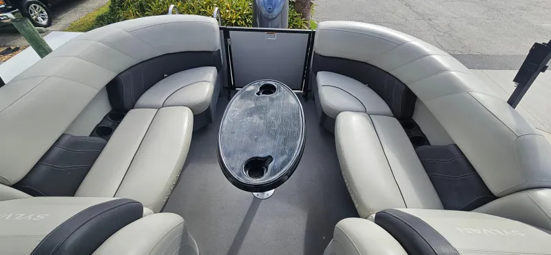 Slide: The Image of 2023 Sylvan Mirage X3 Tritoon interior with gray seating and oval table. - 6