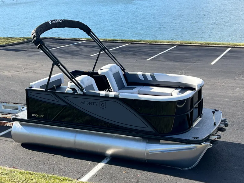 Slide: The Image of 2025 Godfrey Mighty G 1476 C pontoon boat parked by a lake. - 1