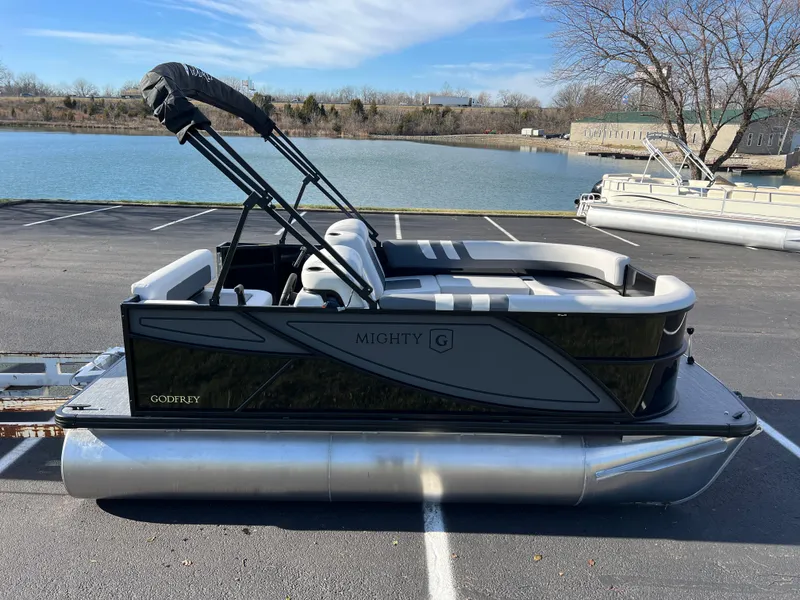 Slide: The Image of 2025 Godfrey Mighty G 1476 C pontoon boat parked by a lake. - 4
