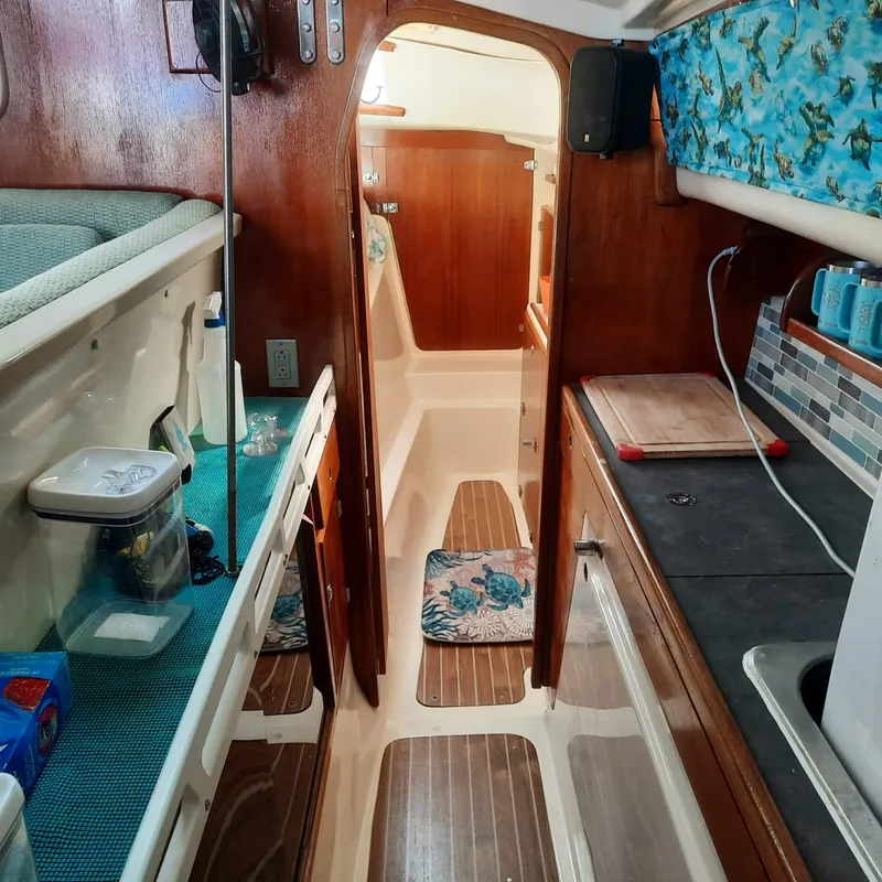 Slide: The Image of Interior of 2006 Gemini 105 MC sailboat, featuring cozy kitchen and wooden cabinetry. - 6