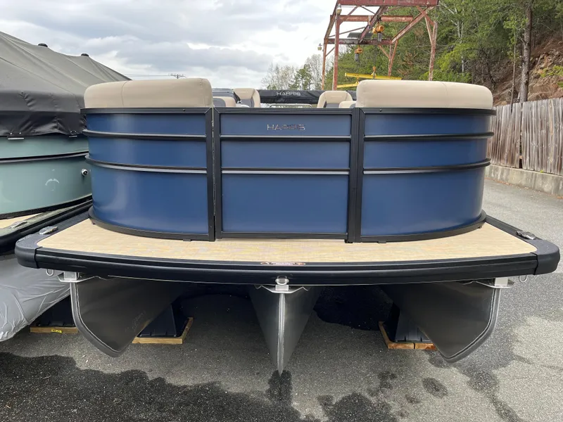 Slide: The Image of 2025 Harris Cruiser 230 pontoon boat, blue exterior, docked on a concrete surface. - 2