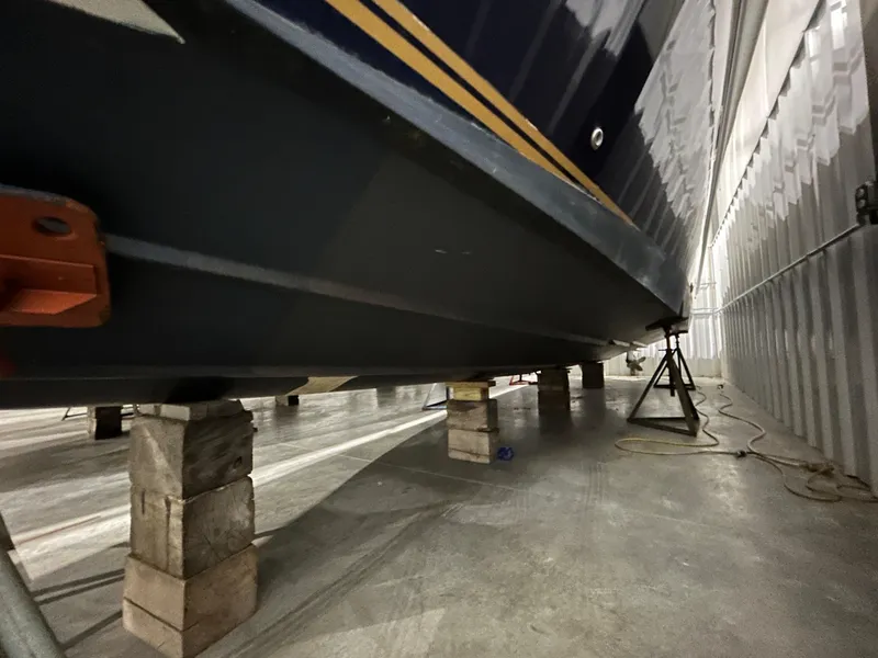 Slide: The Image of 2002 Fountain 38 Express Cruiser in storage, supported by blocks in a warehouse. - 9