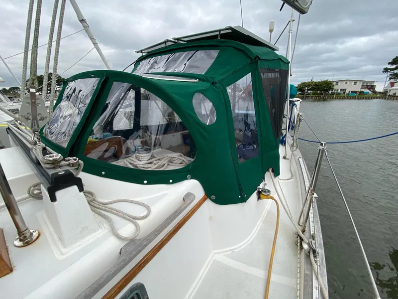 Slide: The Image of 1988 Cabo Rico 38 sailboat with green canopy docked by the water. - 2