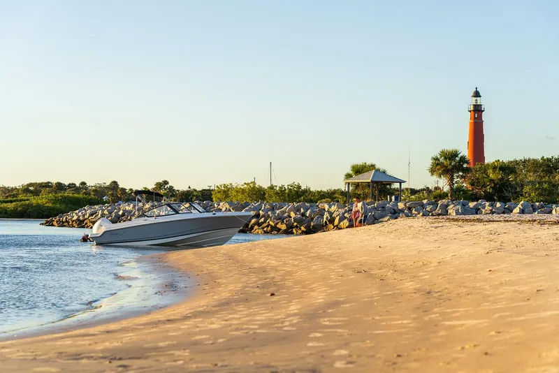 Slide: The Image of 2024 Boston Whaler 210 Vantage on sandy beach near lighthouse at sunset. - 37